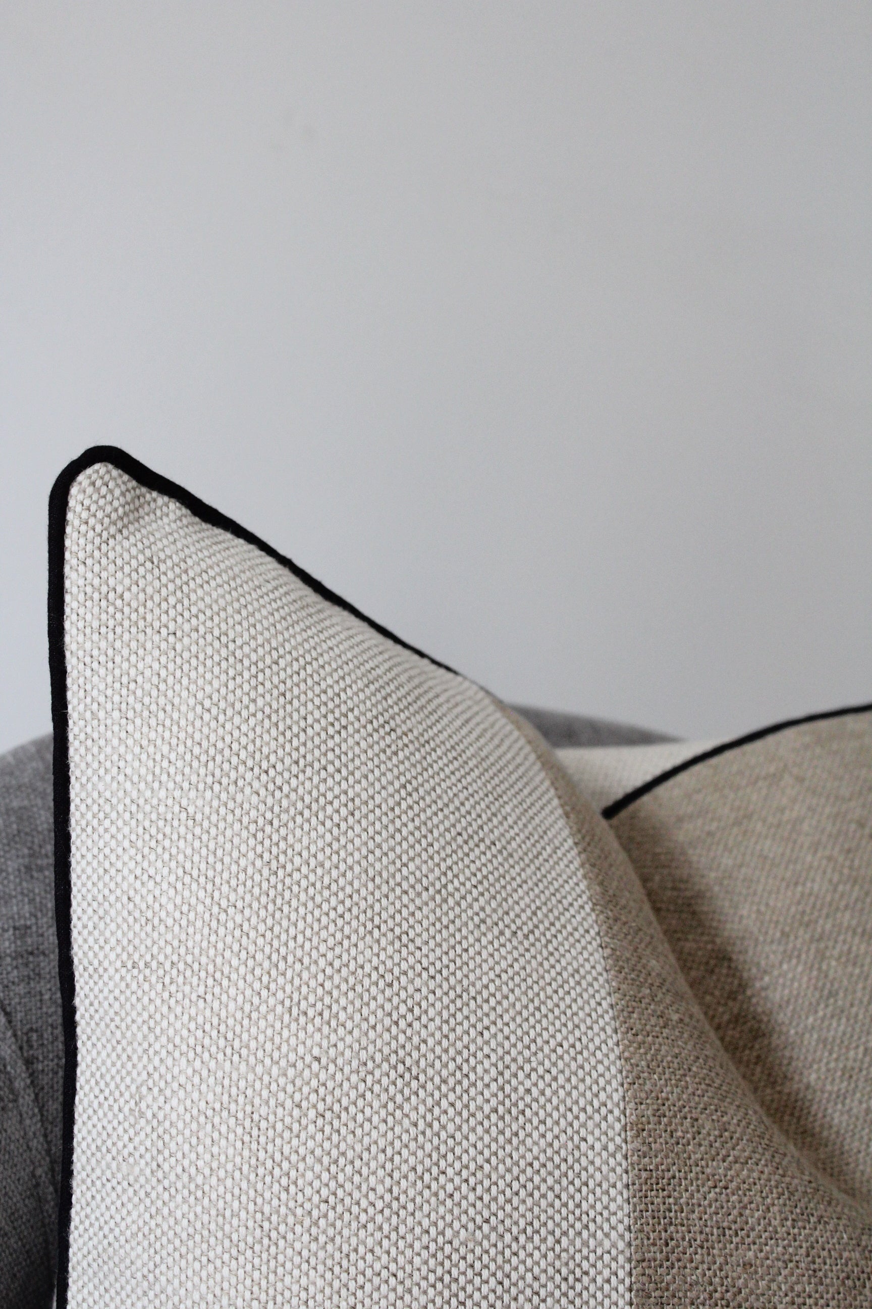 Display statement linen cushion cover in neutral beige tones with black piping edge
